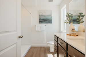 Full bath with vanity, a shower, and light wood-style floors