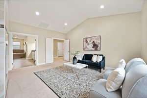 Living area with light carpet, vaulted ceiling, and recessed lighting