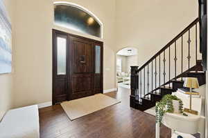 Foyer featuring arched walkways, hardwood / wood-style floors, and a high ceiling