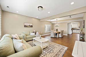 Living area with dark wood-style flooring, arched walkways, hanging lights, and beam ceiling