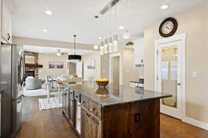 Kitchen featuring stainless steel fridge, hanging light fixtures, dark wood finished floors, and a fireplace
