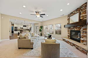 Living area with carpet flooring, ceiling fan, a stone fireplace, and recessed lighting