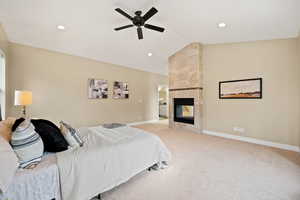 Bedroom with vaulted ceiling, a tiled fireplace, light colored carpet, a ceiling fan, and recessed lighting