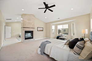 Bedroom featuring lofted ceiling, light colored carpet, a tiled fireplace, recessed lighting, and a ceiling fan
