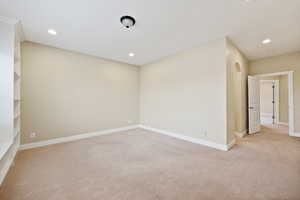 Unfurnished room with light colored carpet, recessed lighting, and arched walkways