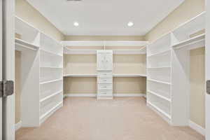 Walk in closet with light colored carpet