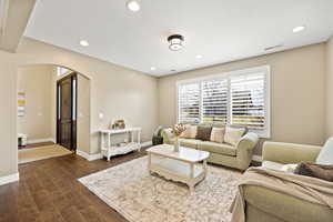 Living area featuring arched walkways, dark wood-style flooring, and recessed lighting