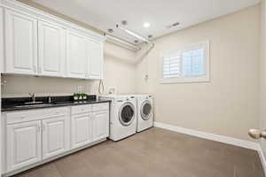 Laundry room featuring washing machine and clothes dryer, cabinet space, and recessed lighting