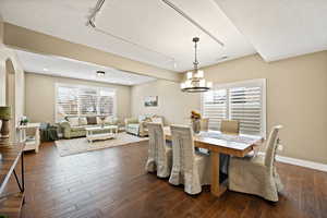 Dining space featuring dark wood-type flooring, suspended lighting, healthy amount of natural light, and arched walkways