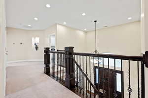 Hall with carpet floors, an upstairs landing, and hanging lights