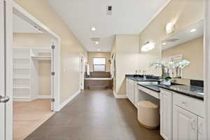 Bathroom featuring a bath, a spacious closet, vanity, dark colored carpet, and recessed lighting