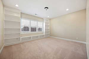 Empty room with light colored carpet and recessed lighting