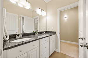 Full bathroom with double vanity and light carpet