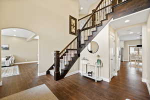 Stairway featuring recessed lighting, hardwood / wood-style floors, a high ceiling, and arched walkways