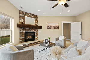 Carpeted living area featuring a ceiling fan, a stone fireplace, and recessed lighting