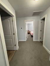 Hall with carpet floors and a textured ceiling