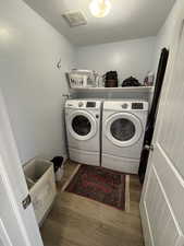 Laundry area with a textured ceiling, wood finished floors, and washer and dryer