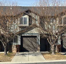 View of front facade featuring stone siding, driveway, a garage, and board and batten siding
