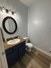 Half bathroom with dark wood finished floors and vanity