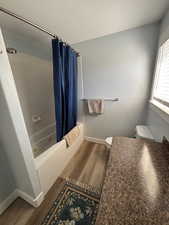 Full bathroom featuring dark wood-type flooring, vanity, shower / bath combo, and a textured ceiling