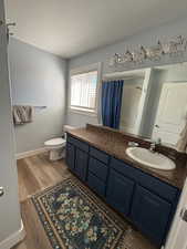 Bathroom with vanity, dark wood-style floors, a textured ceiling, and a shower with shower curtain