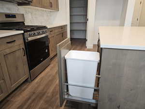 Kitchen with gas range, dark wood-style floors, wood finish cabinets, backsplash, and light stone counters