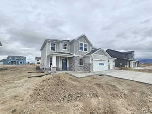 Craftsman house featuring board and batten siding, stone siding, driveway, covered porch, and an attached garage