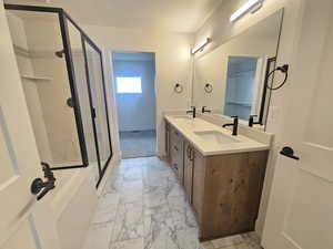 Full bath with a stall shower, light marble finish floors, and double vanity