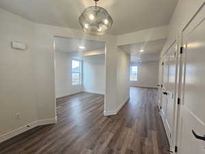 Unfurnished dining area featuring dark wood-style flooring, hanging lights, and healthy amount of natural light