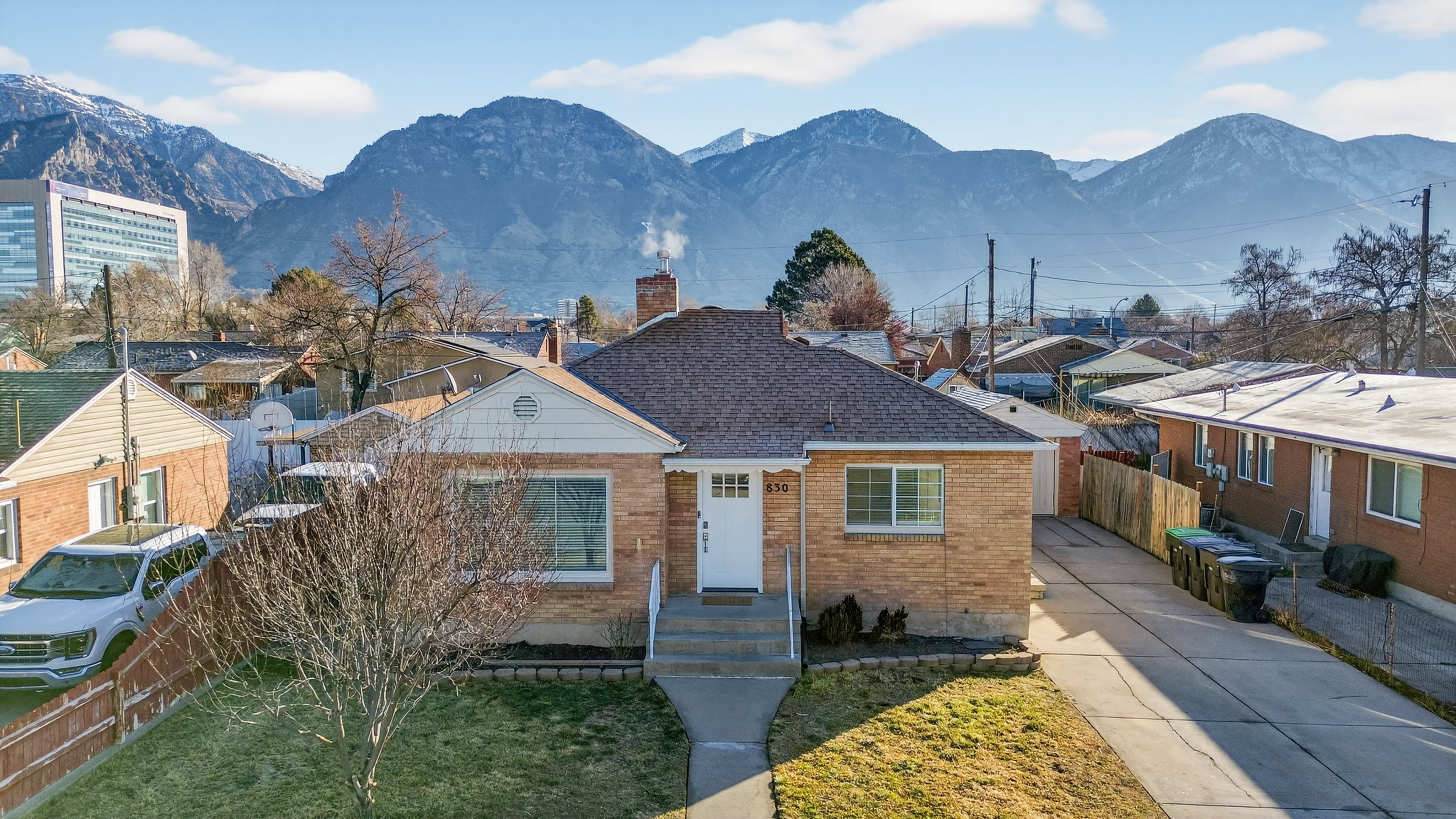 View of front facade with brick siding, a chimney, a residential view, roof with shingles, and concrete driveway