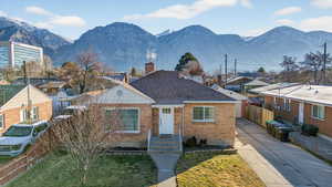 View of front facade with brick siding, a chimney, a residential view, roof with shingles, and concrete driveway