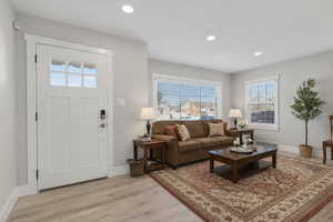 Living room with healthy amount of natural light, light wood-style floors, and recessed lighting