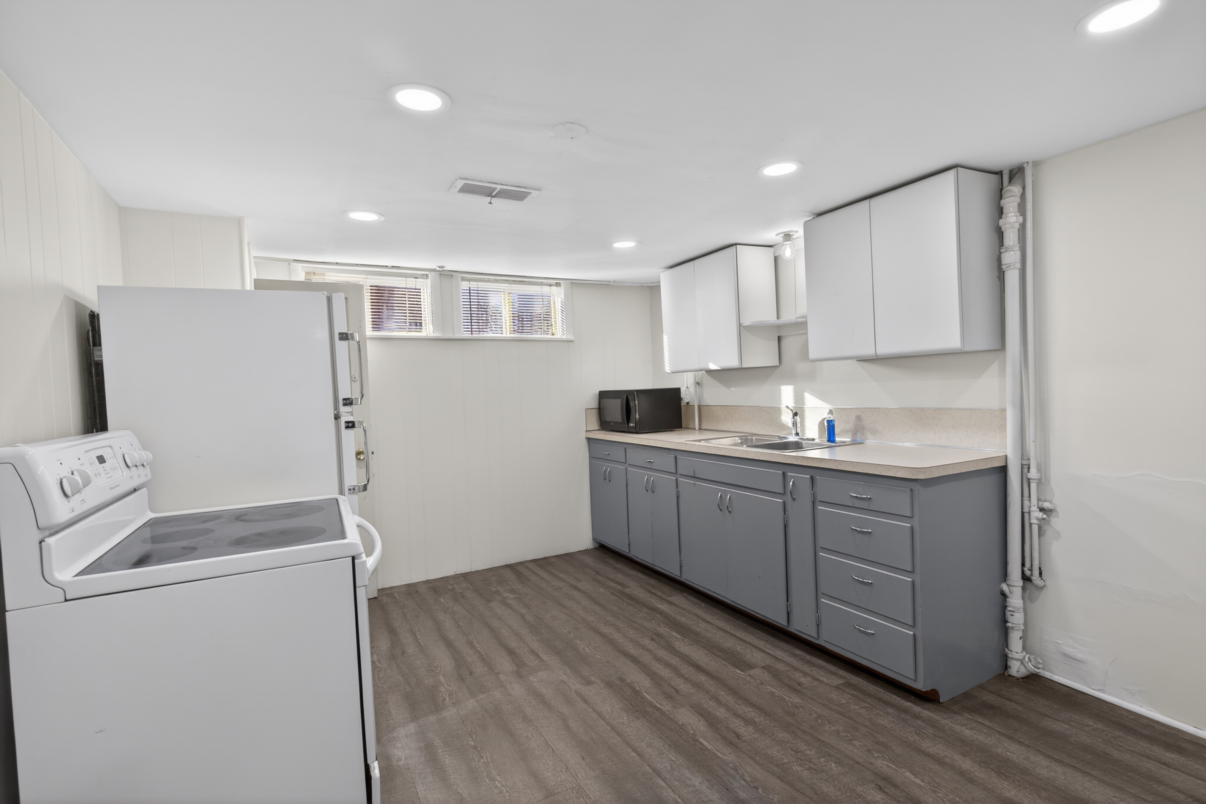 Kitchen featuring dual tone cabinets, white appliances, recessed lighting, dark wood-style floors, and light countertops