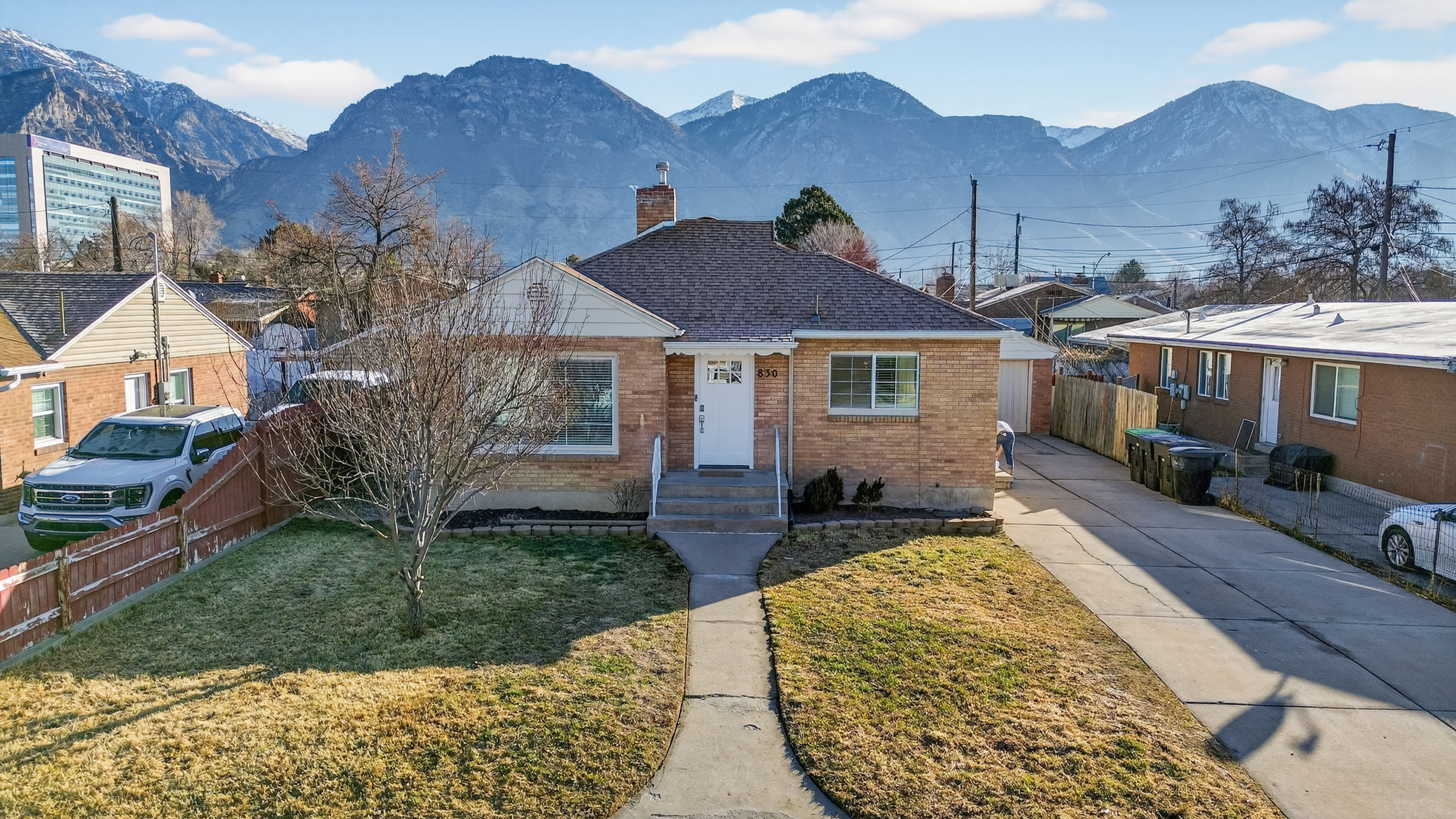 Bungalow-style home featuring brick siding, a chimney, a mountain view, a shingled roof, and concrete driveway