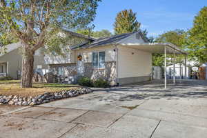 View of front of house with driveway, a shed, and a carport