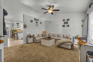 Carpeted living area with vaulted ceiling and ceiling fan