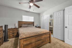 Bedroom featuring two closets, light colored carpet, a ceiling fan, and a textured ceiling