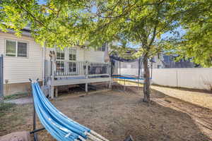 Fenced backyard featuring a trampoline and a deck
