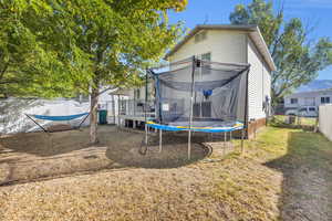 Rear view of house with a trampoline, a fenced backyard, and a gate