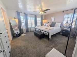 Carpeted bedroom featuring a textured ceiling and ceiling fan