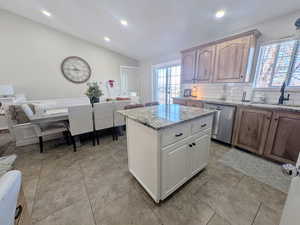 Dual tone kitchen featuring light stone counters, dishwasher, recessed lighting, tasteful backsplash, and vaulted ceiling