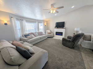 Carpeted living area with a glass covered fireplace, ceiling fan, and recessed lighting