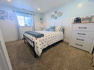 Bedroom featuring a decorative wall, wainscoting, carpet, and recessed lighting