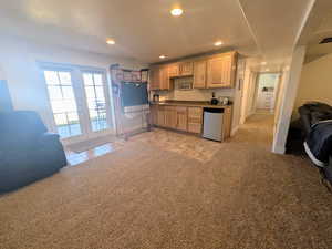 Kitchen with open floor plan, dark countertops, light wood finish cabinetry, recessed lighting, and french doors