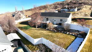 Back of house with a fenced backyard, a patio area, a balcony, and a mountain view