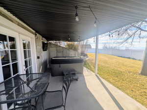 View of patio / terrace with a hot tub and outdoor dining space