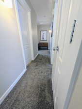 Hall with dark carpet and baseboards