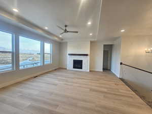 Unfurnished living room with a ceiling fan, light wood finished floors, a fireplace, and suspended lighting