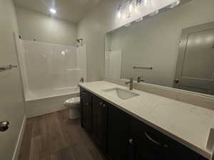 Full bath with vanity, dark wood finished floors, and shower / washtub combination
