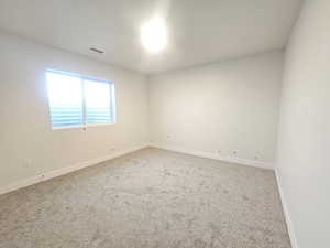 Carpeted spare room featuring baseboards